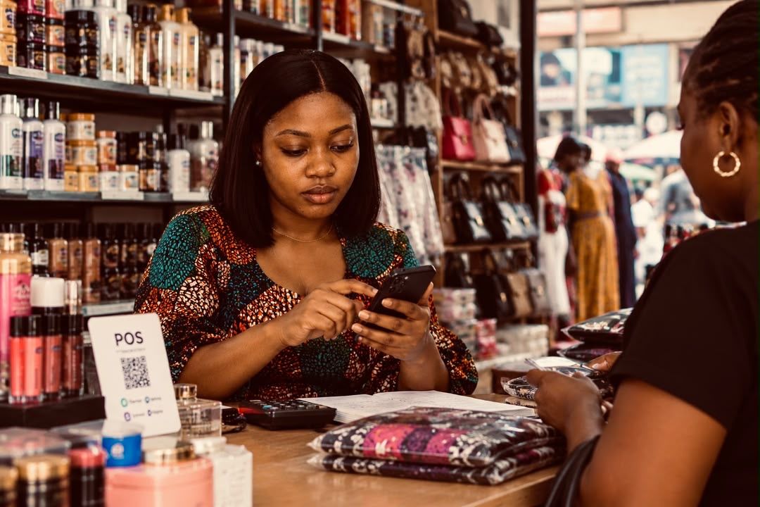 A shop owner recording a sale on her phone at the counter