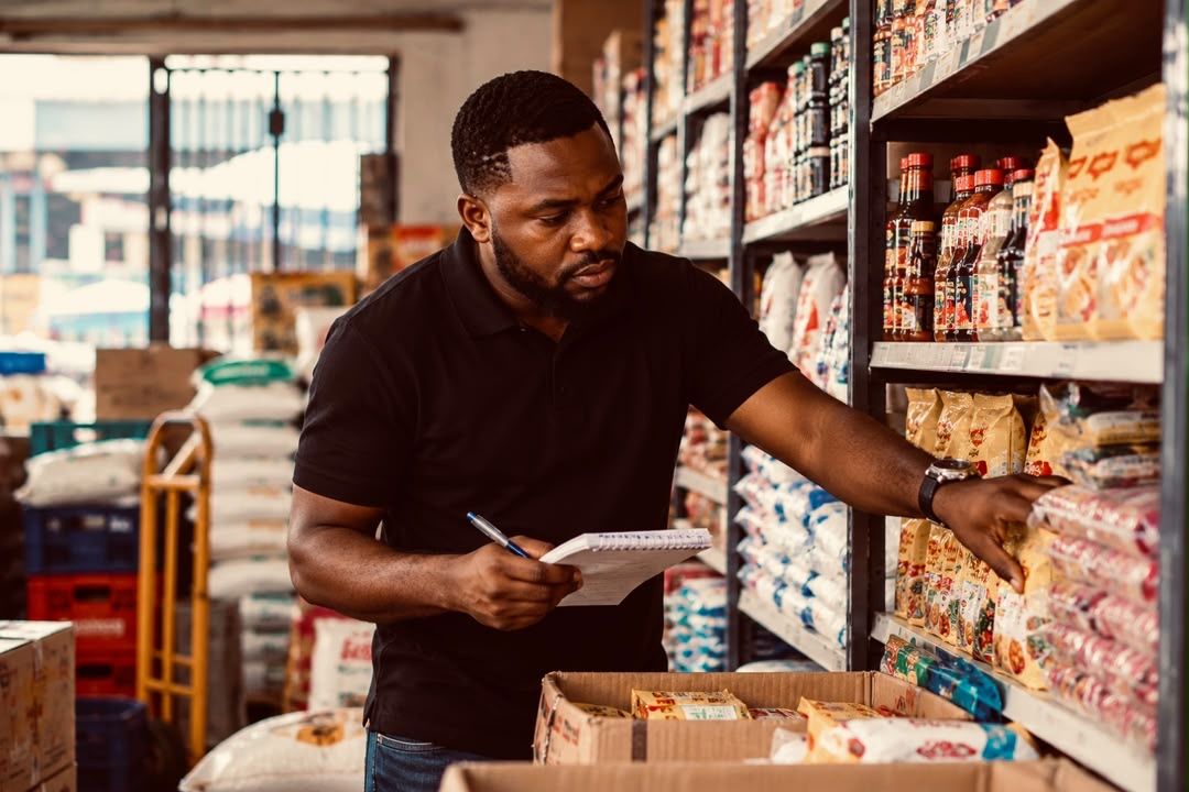 A shop owner counting stock on the shelves